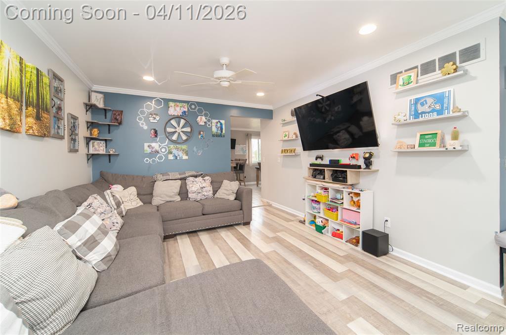 Living room featuring ornamental molding, light wood-style floors, a ceiling fan, and recessed lighting