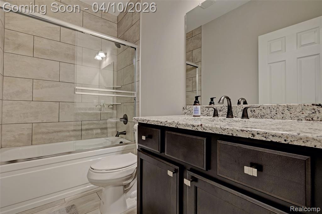 Bathroom with vanity and combined bath / shower with glass door