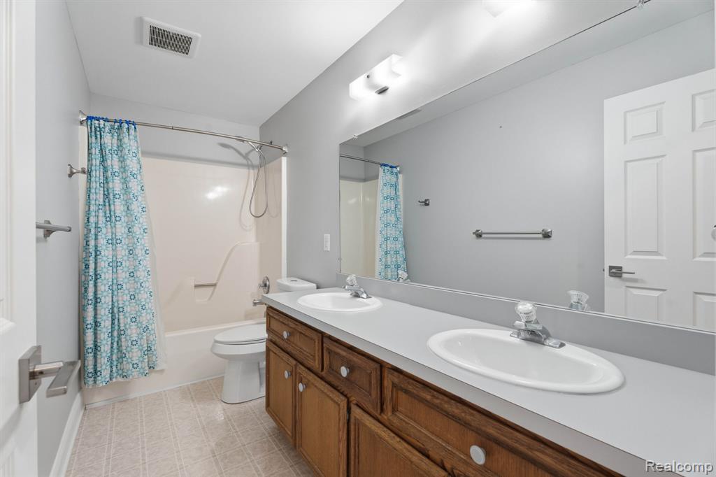 Bathroom with double vanity and shower / tub combo with curtain