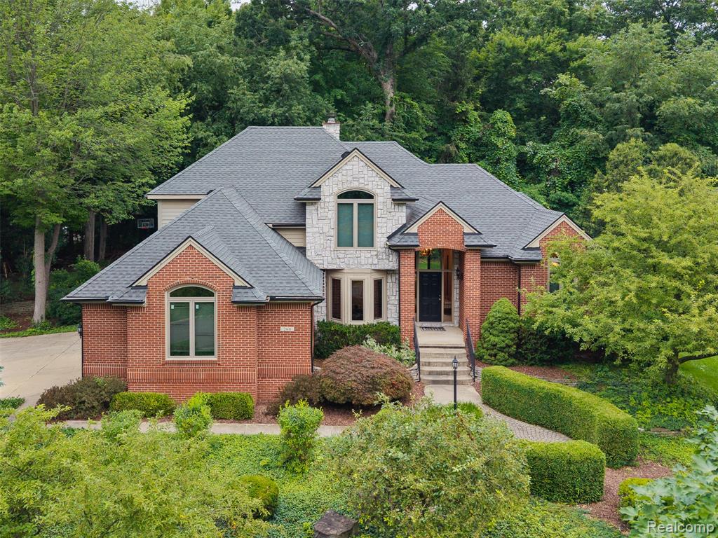 French country inspired facade featuring stone siding, brick siding, roof with shingles, and a chimney