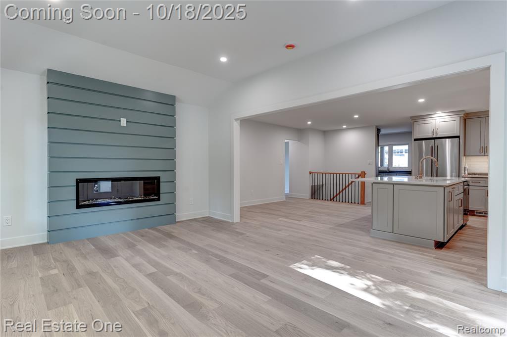 Unfurnished living room featuring recessed lighting, a large fireplace, light wood finished floors, and lofted ceiling