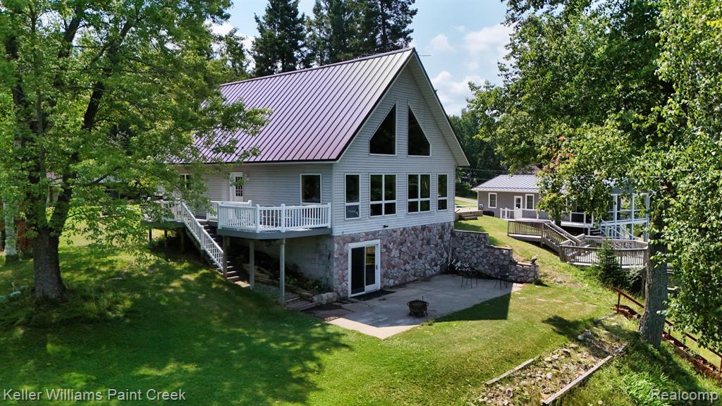 Multi-level dwelling featuring a metal roof, an expansive deck with white railings, and a stone facade