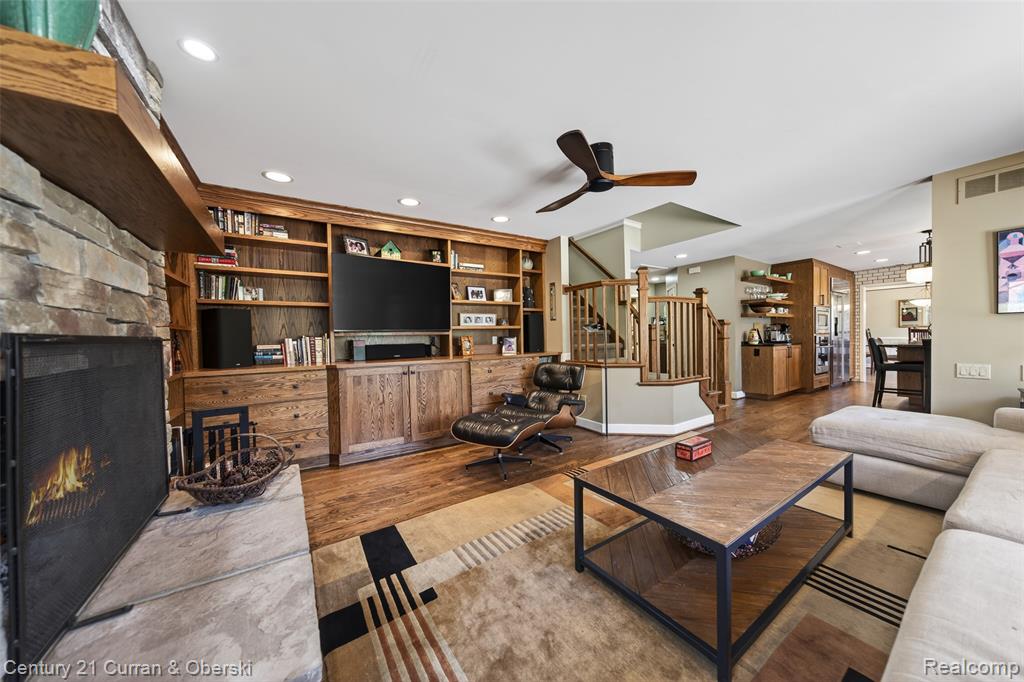 Living area featuring a fireplace, a ceiling fan, wood finished floors, recessed lighting, and built in features