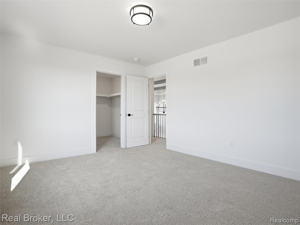 Unfurnished bedroom featuring a walk in closet and light colored carpet
