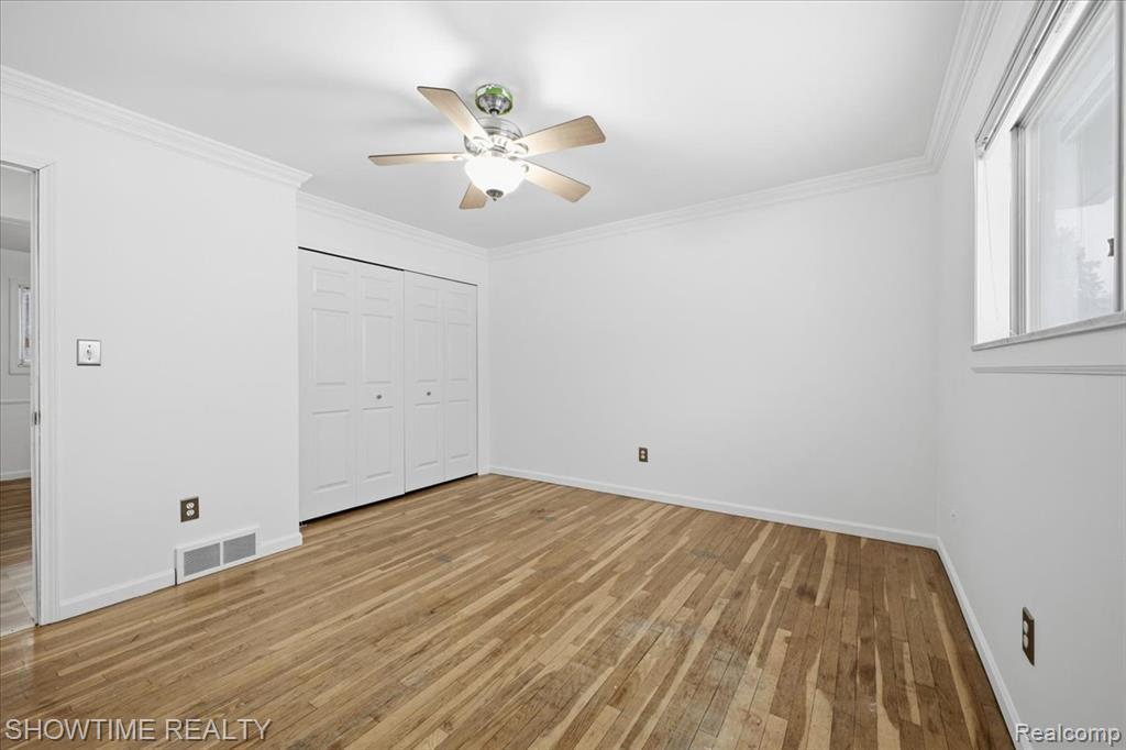 Unfurnished bedroom featuring light wood-type flooring, crown molding, ceiling fan, and a closet