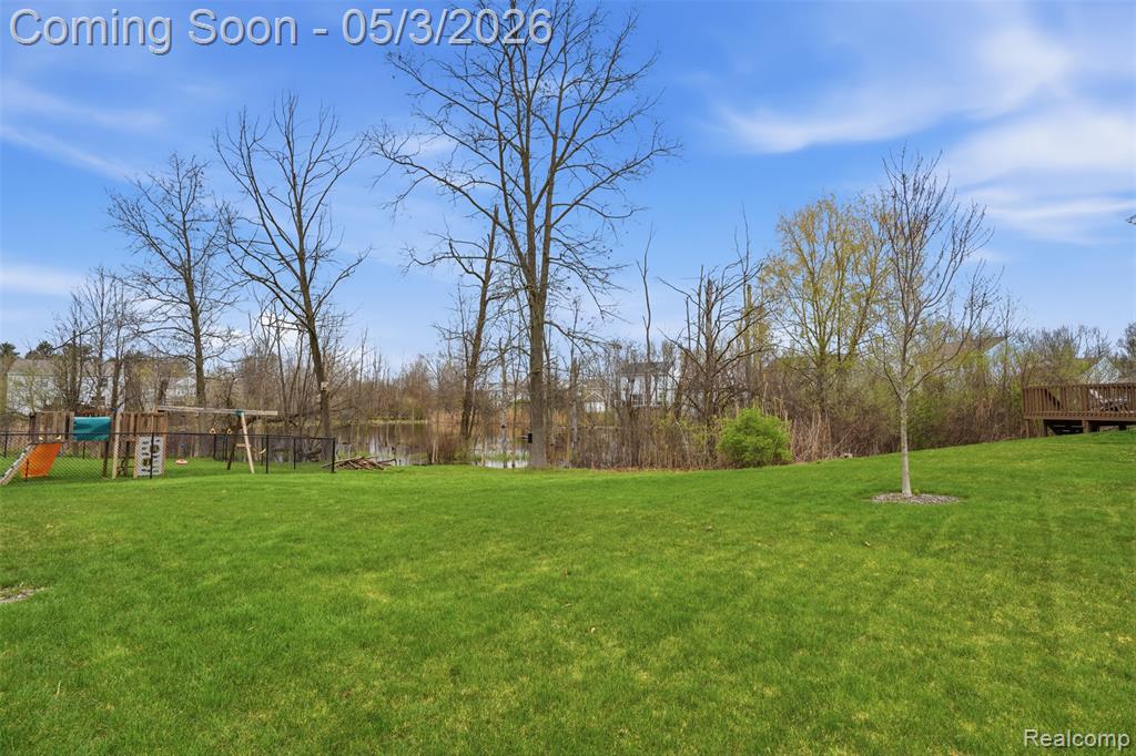 View of grassy yard with a wooden deck