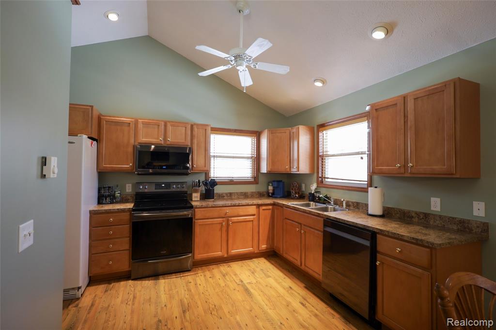 Kitchen featuring electric stove, stainless steel microwave, a ceiling fan, freestanding refrigerator, and dishwashing machine