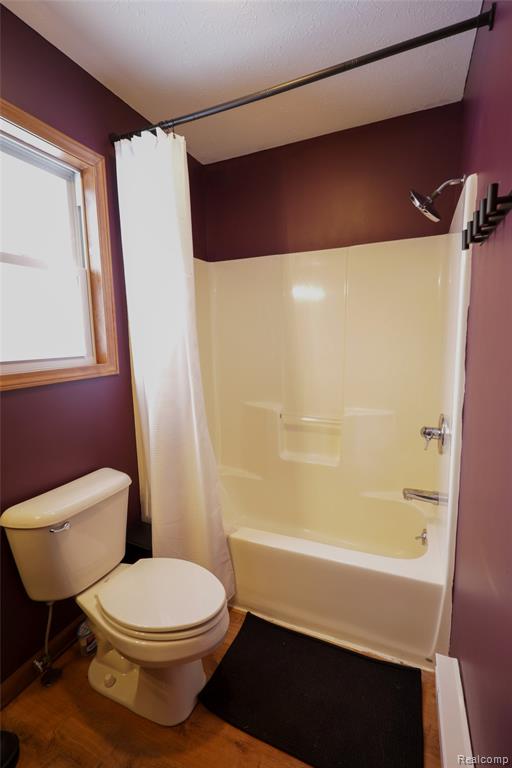 Bathroom with shower / bath combination with curtain and light wood-style floors