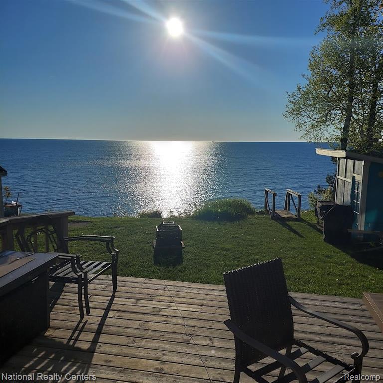 Expansive water frontage with a wooden deck, a grassy lawn, and a small structure