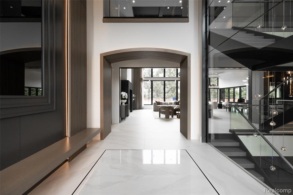 Hallway with light marble finish floors, a towering ceiling, arched walkways, and stairway