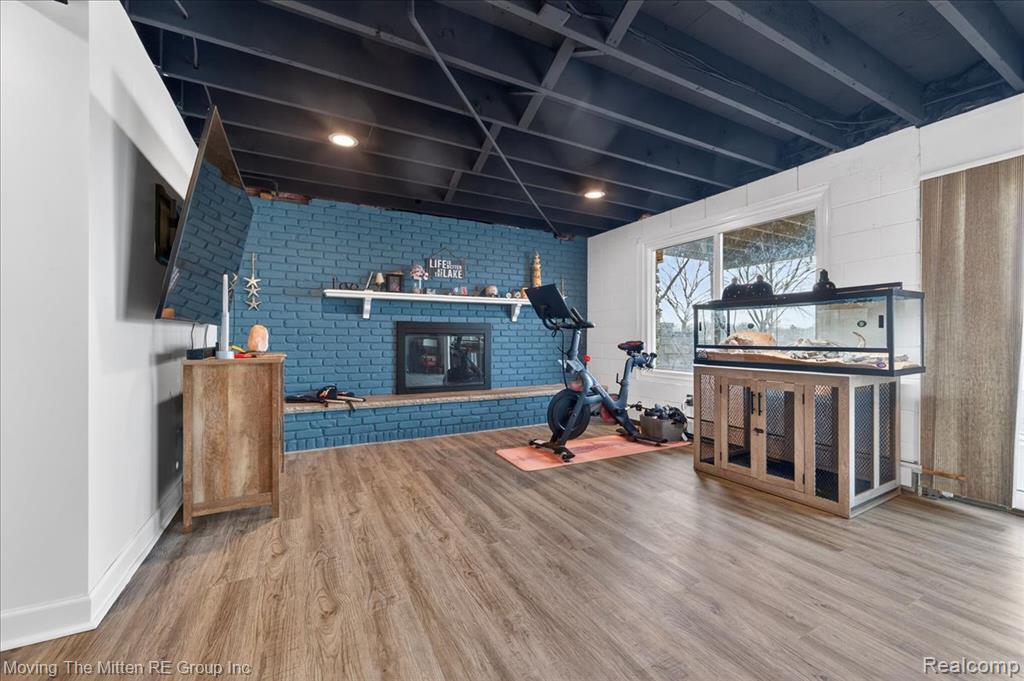 Exercise room with brick wall, a fireplace, and wood finished floors