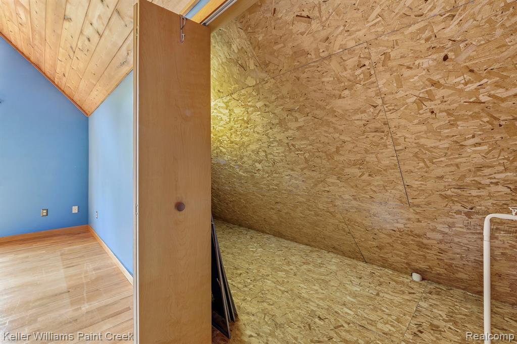 Sloped wood-paneled ceiling, wood-finish flooring, and a light-colored wood-finish door