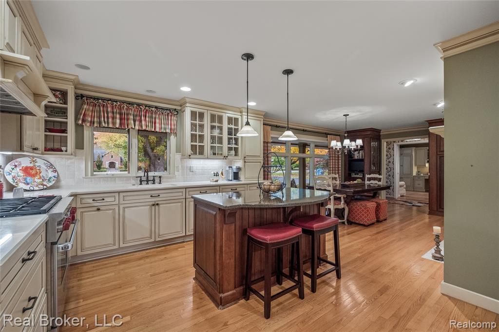 Kitchen featuring cream cabinetry, luxury range, premium range hood, glass insert cabinets, and pendant lighting