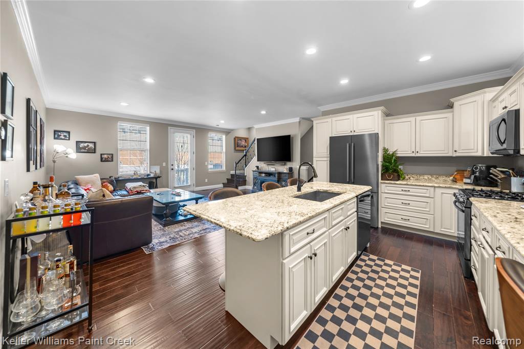 Kitchen with black gas range oven, dark wood-style floors, recessed lighting, crown molding, and open floor plan