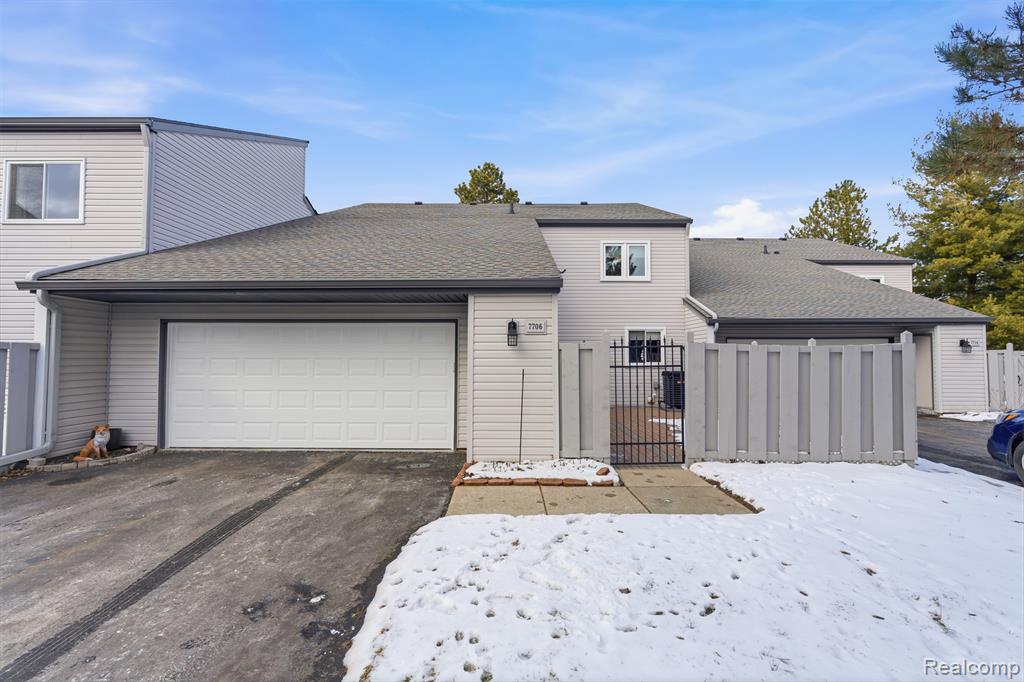 View of front of home with a shingled roof, a gate, an attached garage, and driveway