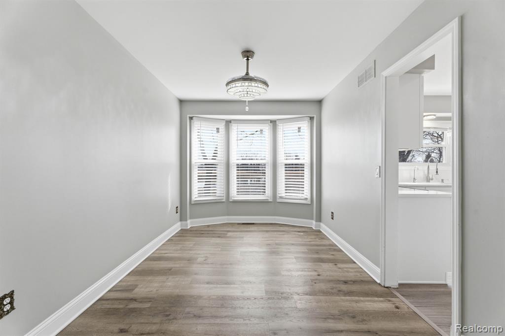 Unfurnished dining area with dark wood-style floors and baseboards