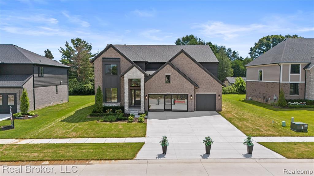French country home featuring driveway, a front lawn, brick siding, and a garage