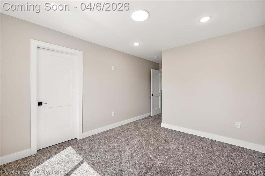 Carpeted empty room with baseboards and recessed lighting