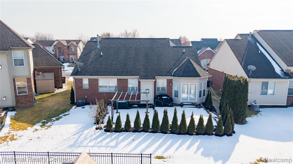 View of front of home with brick siding, a shingled roof, and a residential view