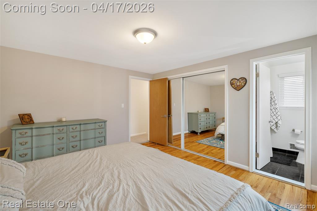 Bedroom with ensuite bathroom, light wood-style flooring, and a closet