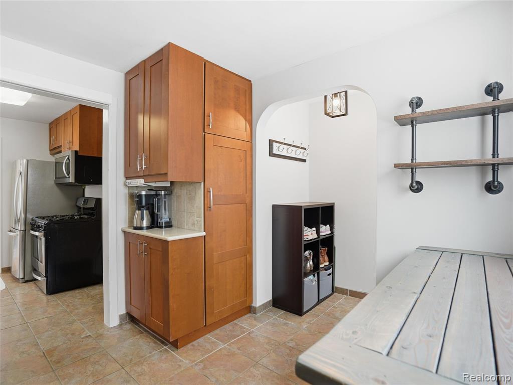 Kitchen featuring wood finish cabinetry, stainless steel appliances, decorative backsplash, arched walkways, and open shelves