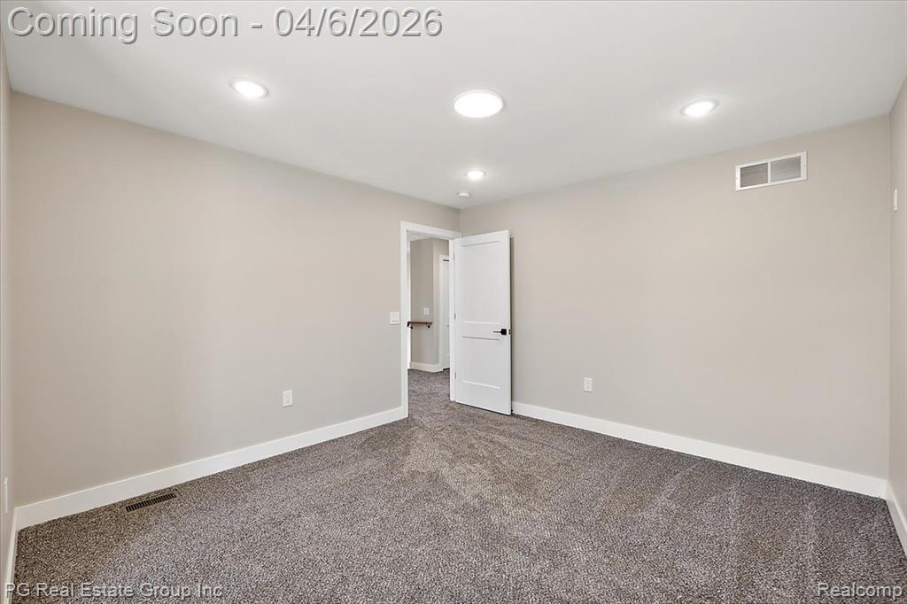 Unfurnished room with dark colored carpet and recessed lighting