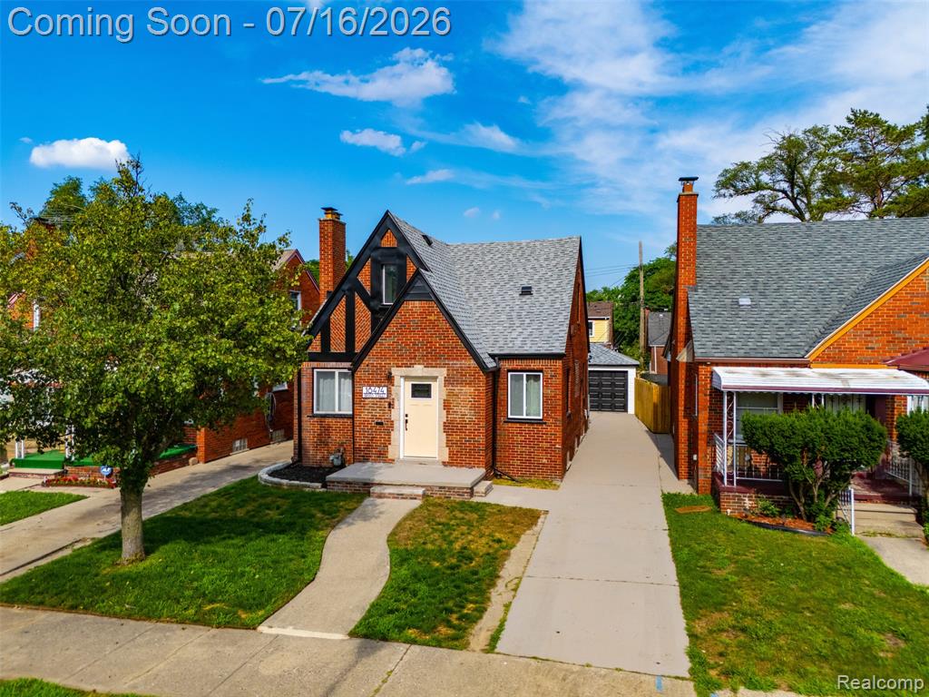 Brick bungalow featuring a steeply pitched shingle roof and a cream-colored entry door