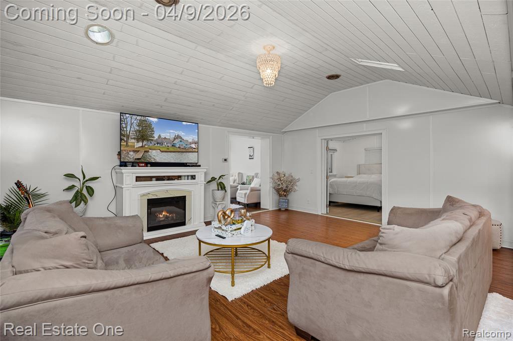 Living room with wood finished floors, a glass covered fireplace, and wood ceiling