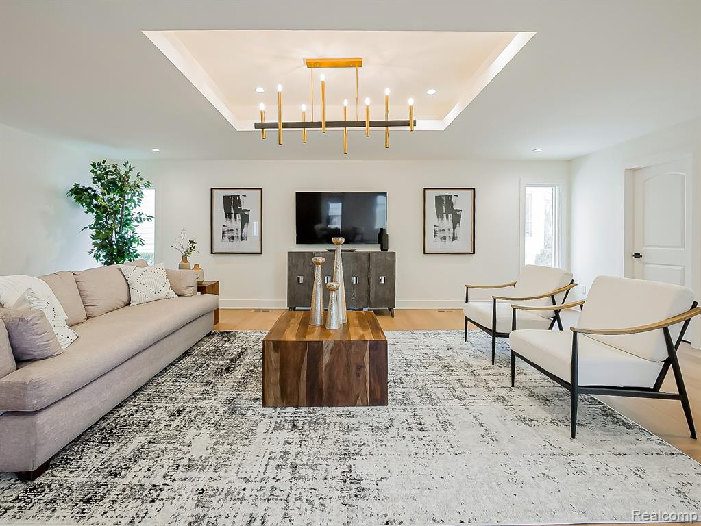 Living room featuring a tray ceiling and light wood-style floors