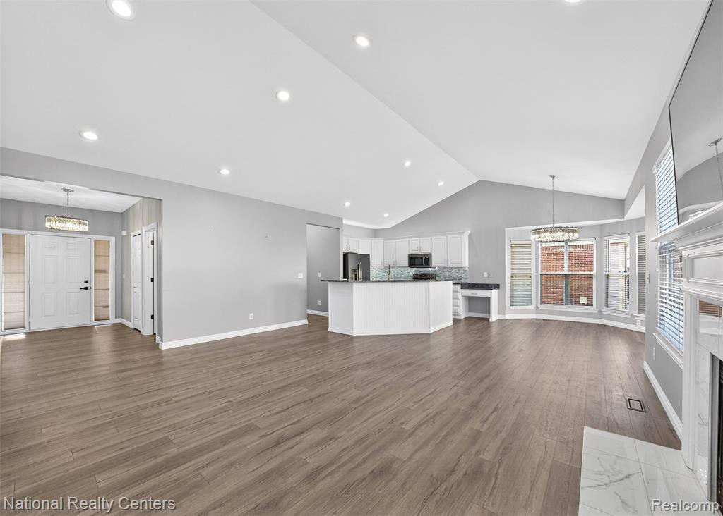 Unfurnished living room featuring a chandelier, dark wood-style floors, a premium fireplace, and vaulted ceiling