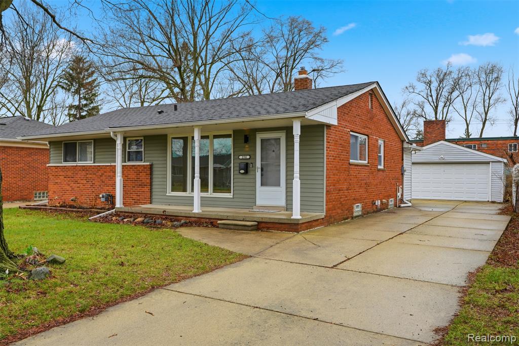 View of front of home featuring a detached garage, brick siding, an outbuilding, a porch, and a chimney