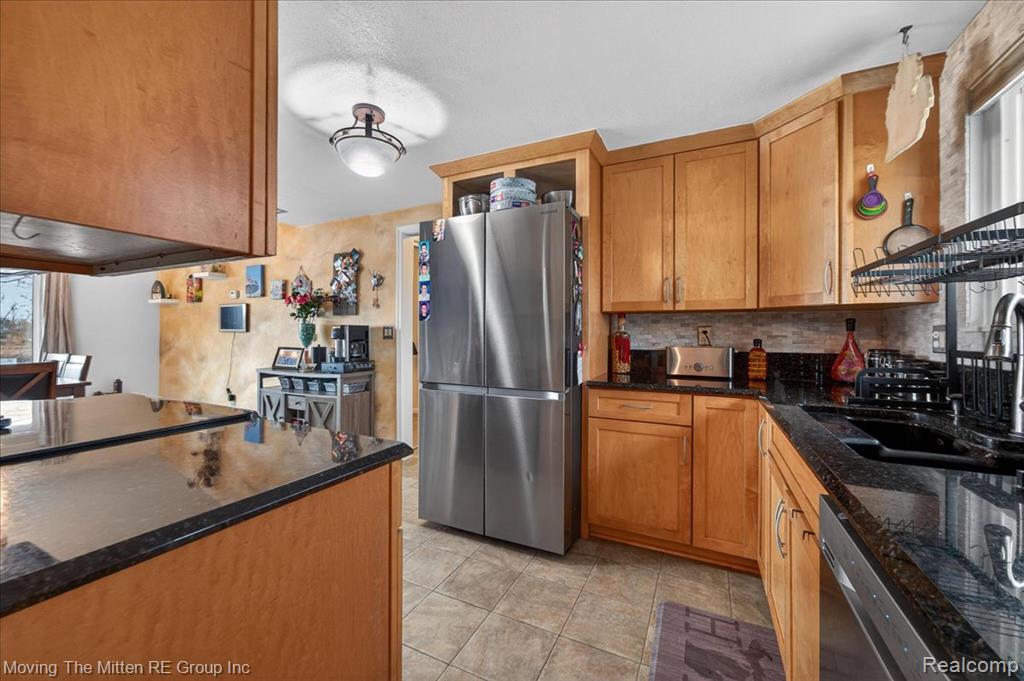 Kitchen with stainless steel appliances, plenty of natural light, dark stone counters, and tasteful backsplash