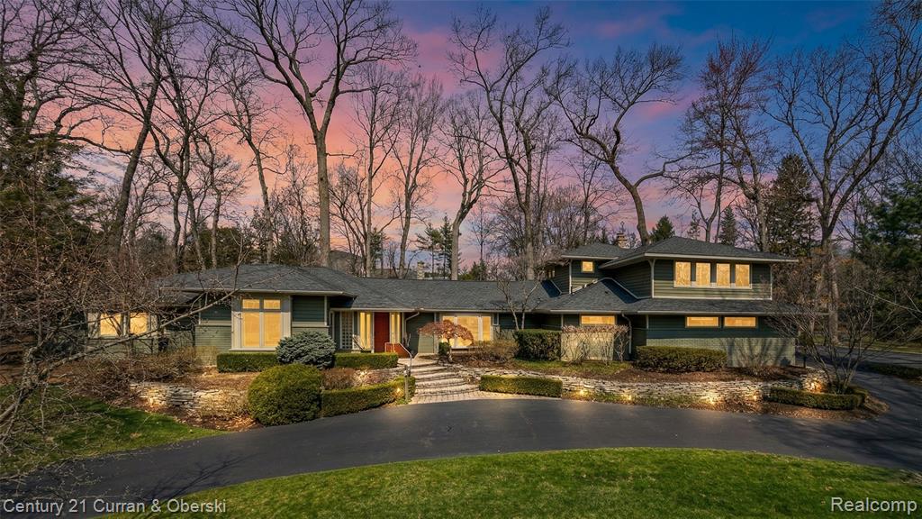Prairie-style house featuring a front lawn and view of wooded area